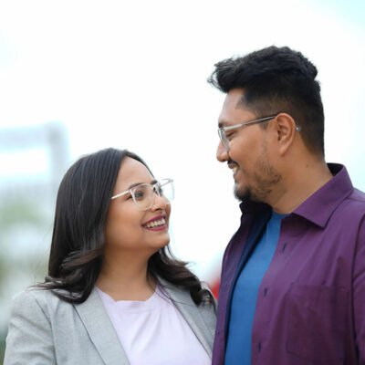 Pre wedding photography of smiling couple looking at each other outdoors.